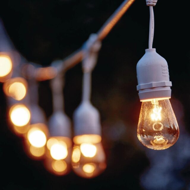 A string of lights with one hanging light bulb.